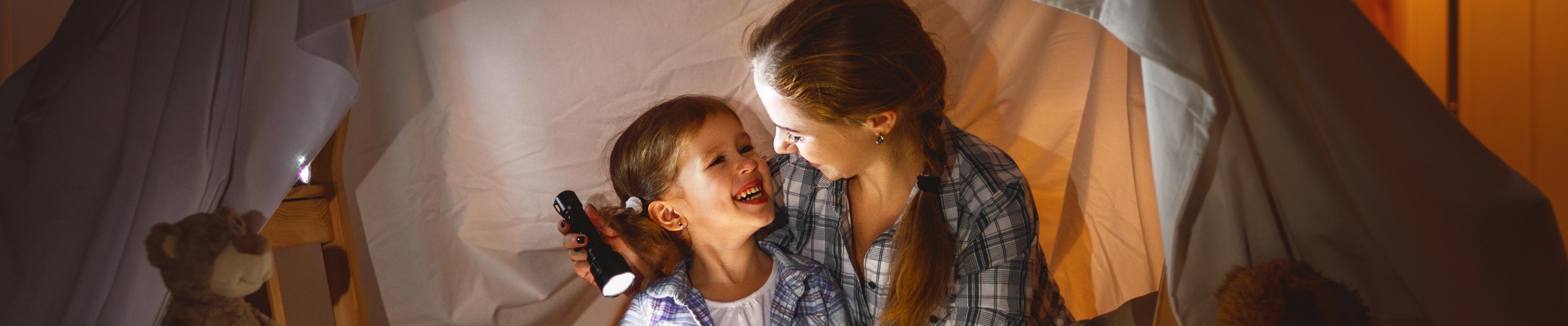 Mother and daughter waiting out a power outage in a fort with flashlights