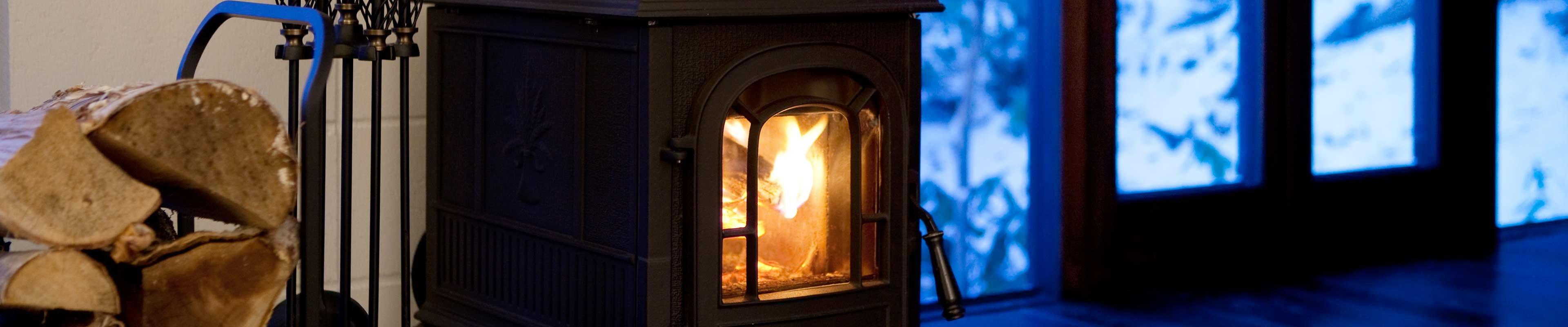 A pile of wood sits next to an upscale wood-burning stove.