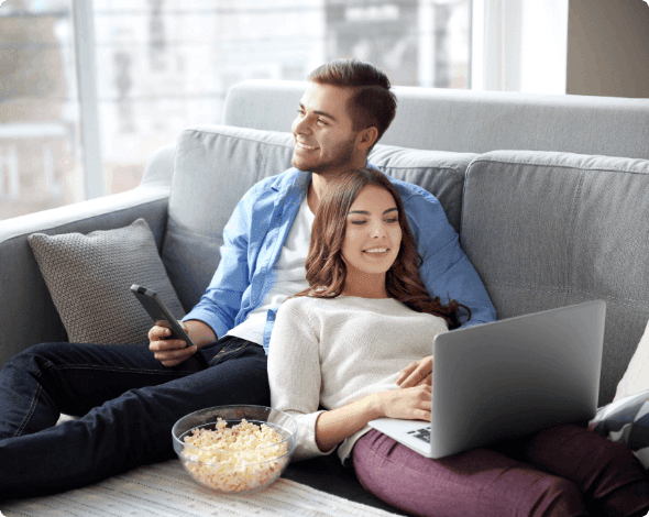 A happy couple lounging on their living room couch.