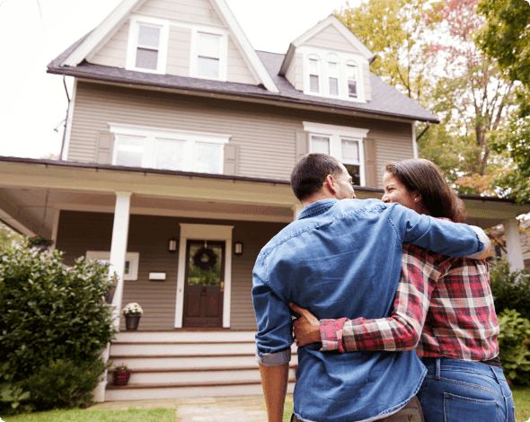 Couple standing in a yard, looking at a new home.