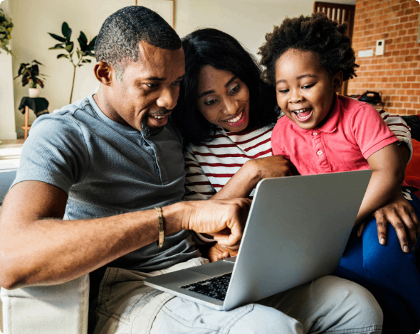 Happy family sitting on their couch while looking at their laptop.