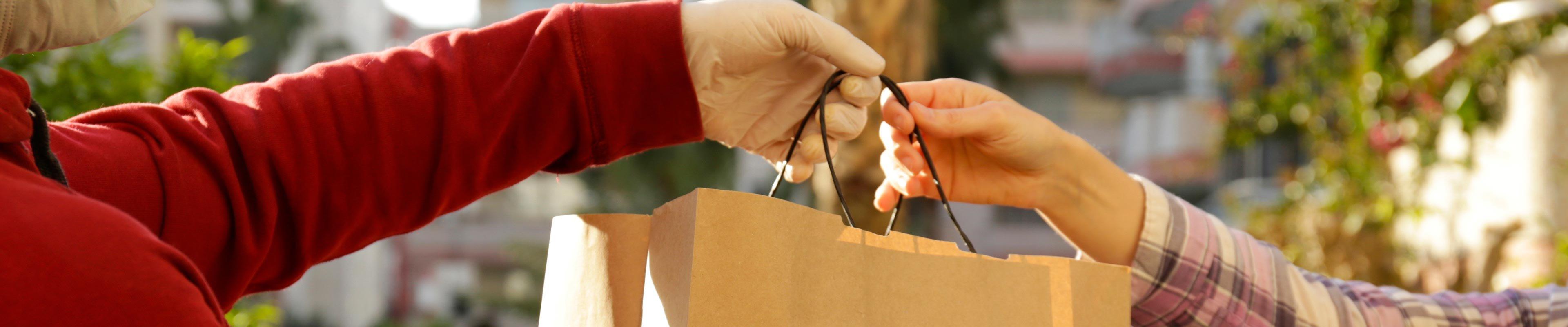 Person in gloves giving someone groceries