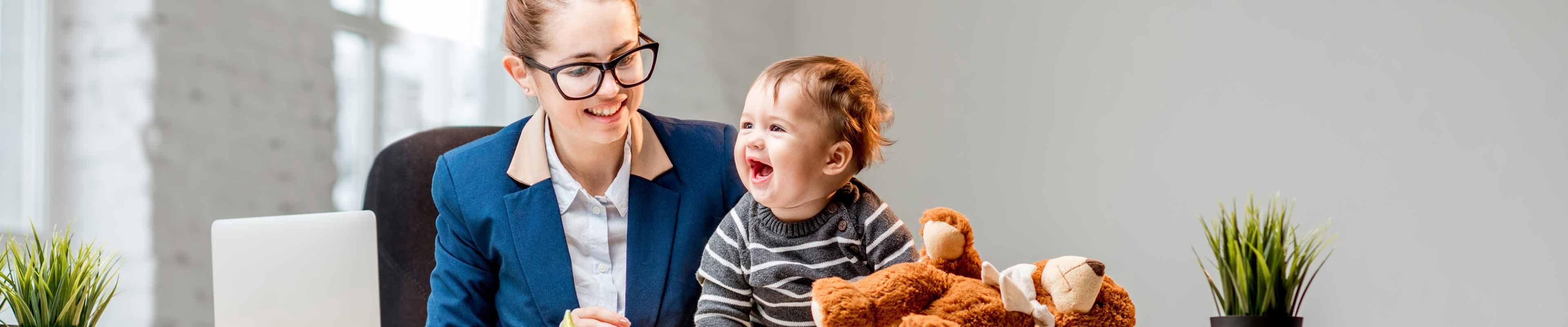 Image of a mother playing with her child while working on the laptop.